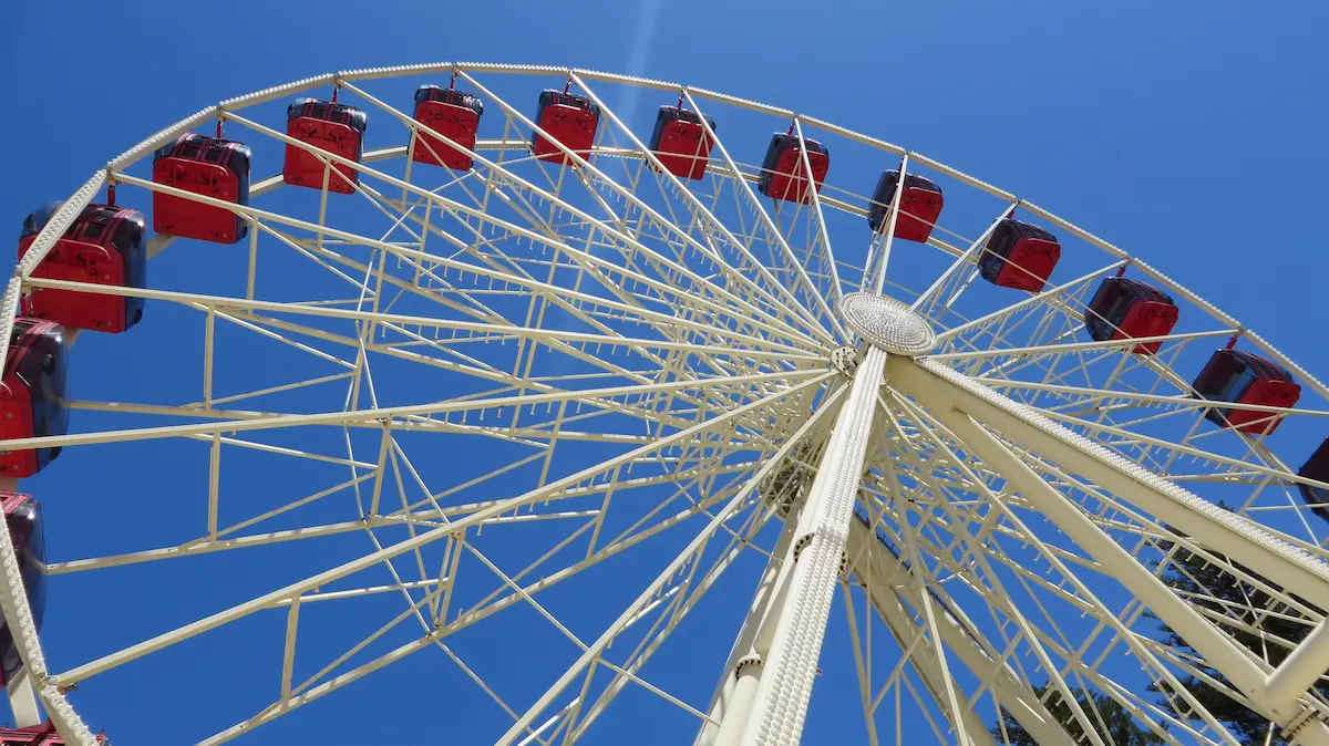 Ferris wheel with red gondolas against a bright blue sky capturing movement perspective adventure and summer fun outdoors