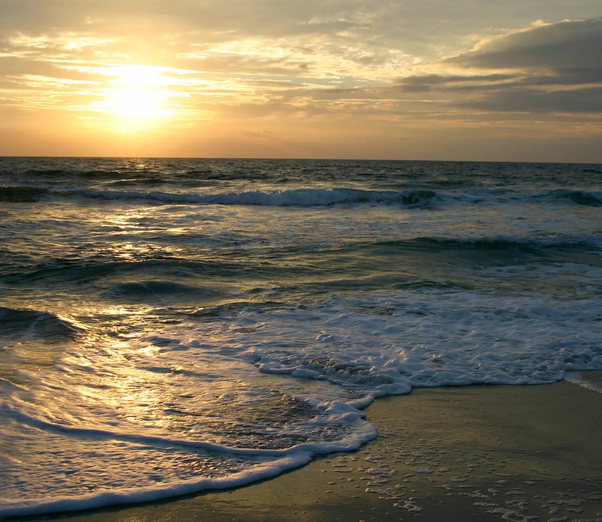 Gentle ocean waves rolling onto a sandy beach at sunset symbolizing calm reflection and emotional healing in trauma therapy annapolis