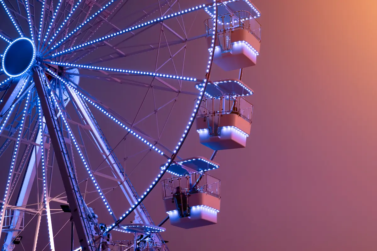 Illuminated ferris wheel cabins glowing against a soft pink and purple evening sky evoking reflection emotional perspective life transitions and the balance between excitement and uncertainty in the healing journey through therapy