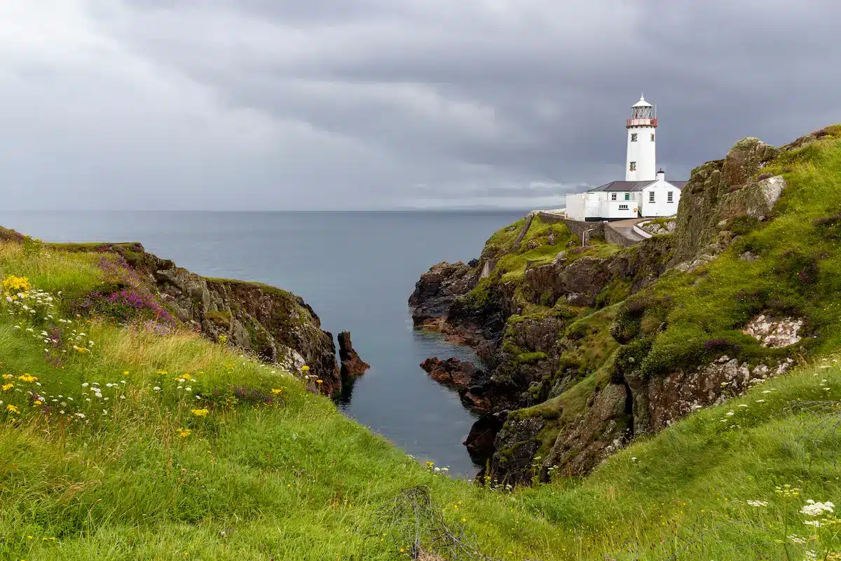 Lighthouse on rocky coastal cliffs beneath storm clouds symbolizing guidance in depth oriented therapy annapolis