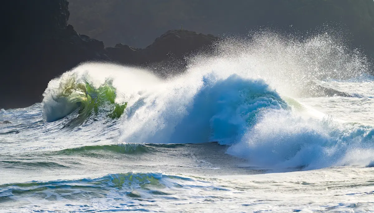 Powerful ocean waves crashing and curling with bright sea spray against a dark rocky backdrop symbolizing emotional intensity resilience release and the strength found through trauma recovery and healing in therapy