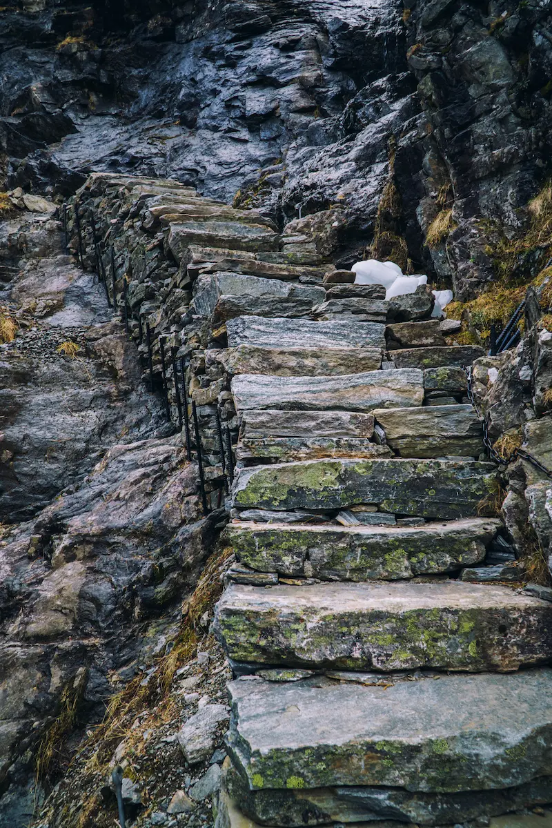 Rugged stone staircase carved into a mountainside cliff symbolizing resilience gradual progress perseverance through challenges and the difficult but meaningful steps often involved in personal growth and emotional healing through therapy